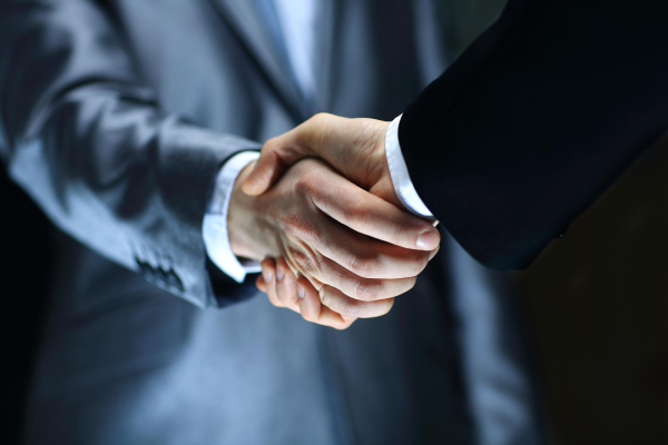 close-up of two men in suits shaking hands