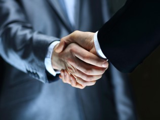 close-up of two men in suits shaking hands